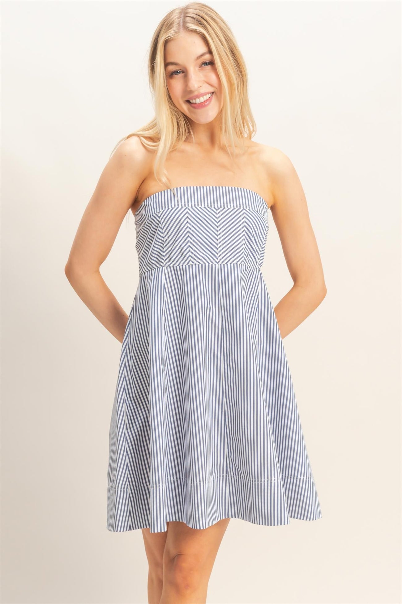 woman wearing a strapless blue and white striped sundress with a fitted bodice and flared skirt