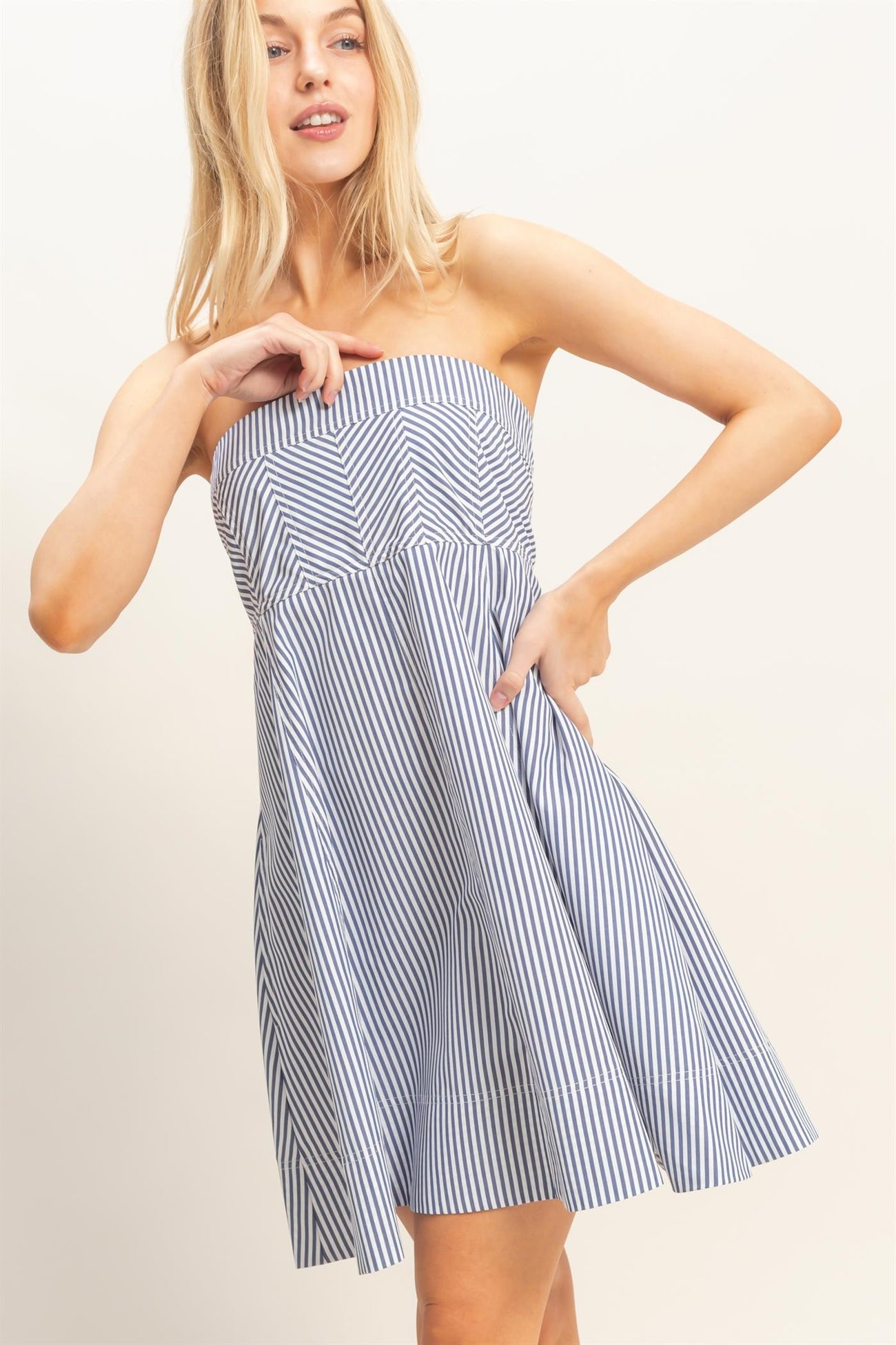 woman wearing a strapless navy and white striped sundress with a flared skirt and pockets