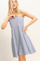 woman wearing a strapless navy and white striped sundress with a flared skirt and pockets