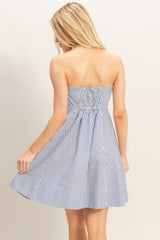 woman wearing a strapless navy and white striped sundress with a smocked back detail