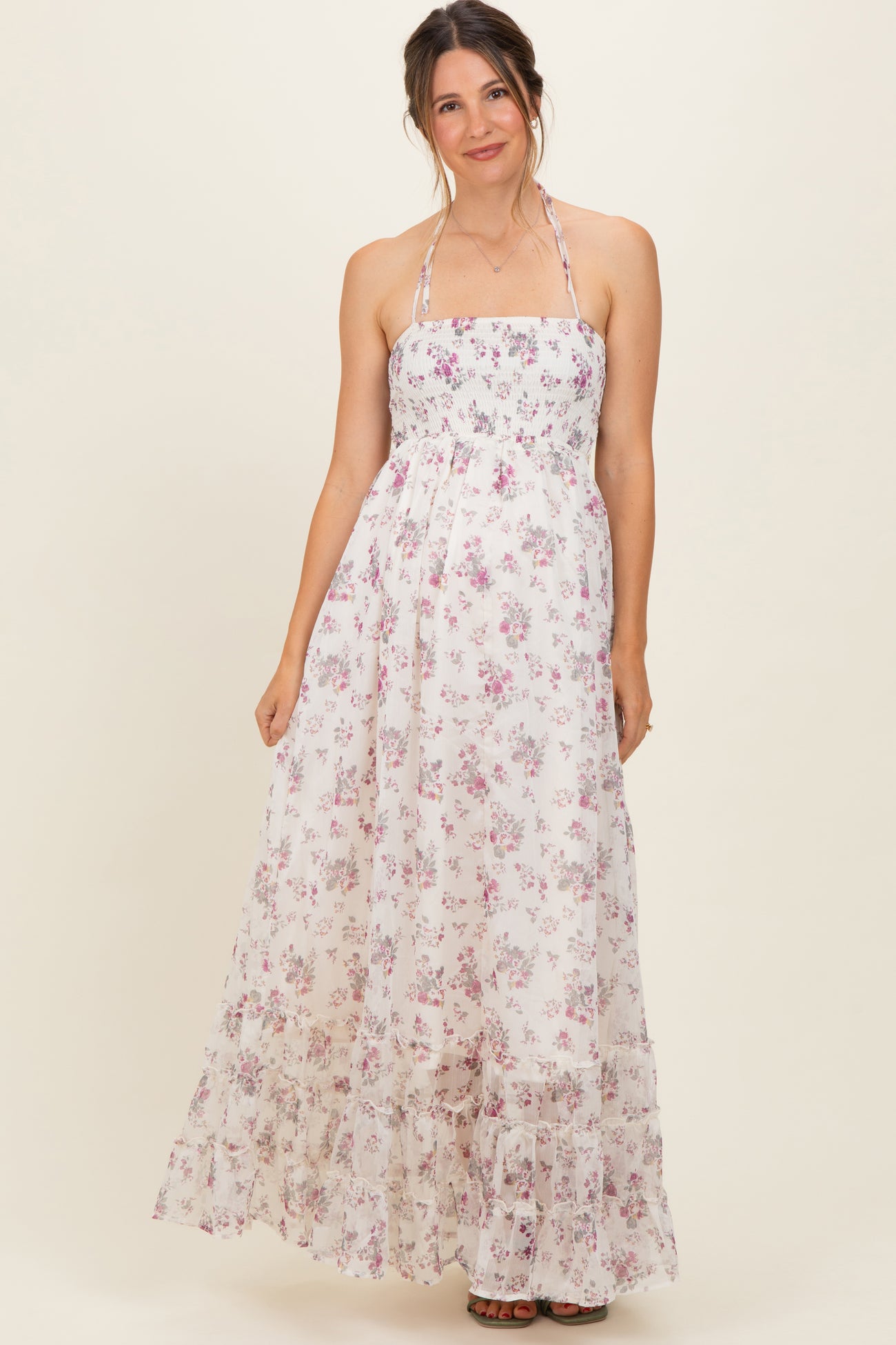 woman wearing a floral maxi maternity dress with a halter neckline and ruffled hem, showing a baby bump