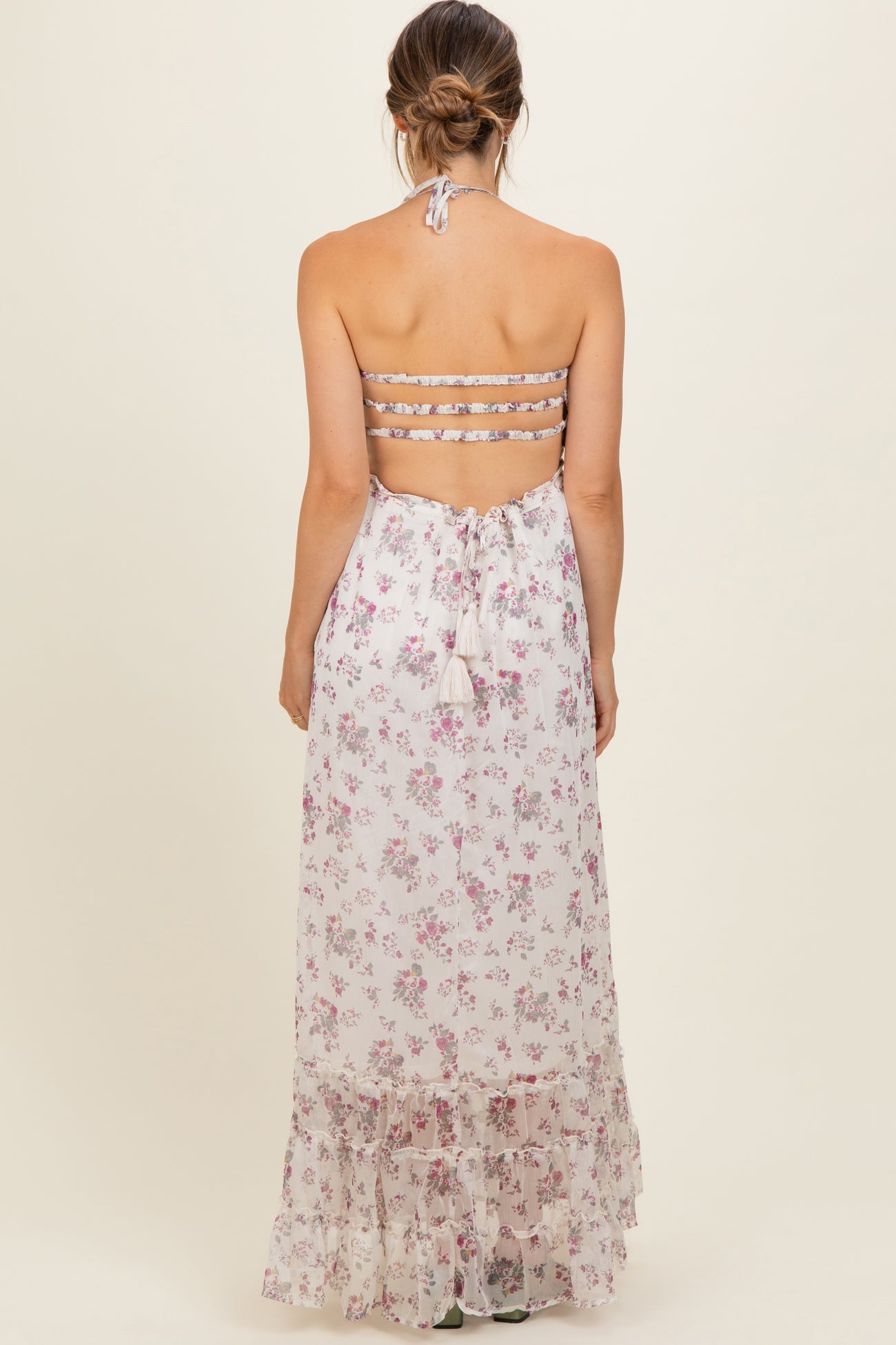 woman wearing a floral print maternity dress with a halter neck and tiered skirt, showing a bare back and back ties