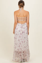 woman wearing a floral print maternity dress with a halter neck and tiered skirt, showing a bare back and back ties