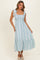 woman wearing a light blue floral maxi dress with tie shoulder straps and a ruffled hem