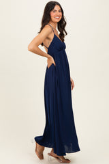 woman wearing a navy blue maxi dress with a halter neck and flowy skirt, smiling while standing sideways