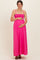 woman wearing a bright pink maternity maxi dress with smocked bodice and holding her baby bump