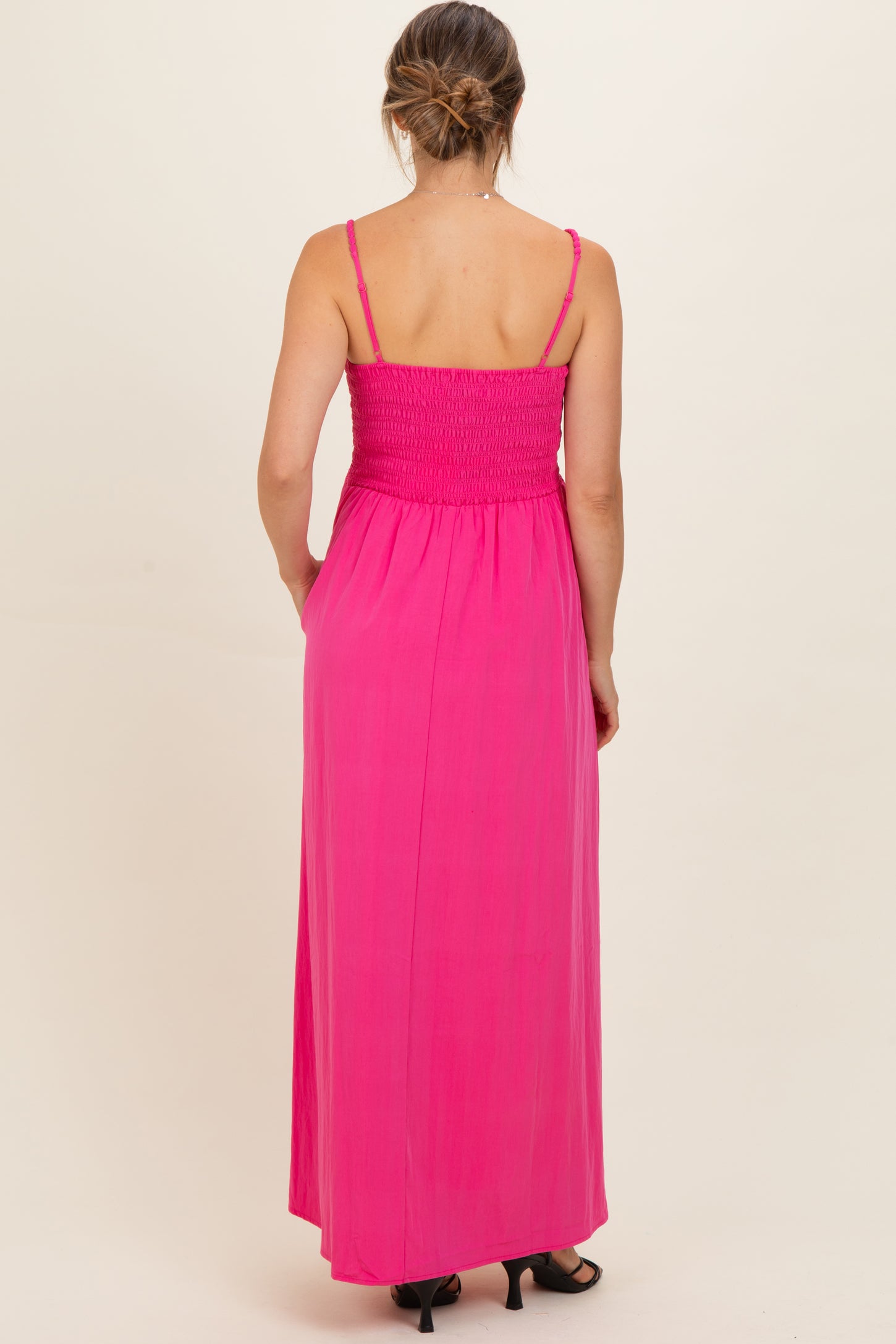 woman wearing a pink maternity maxi dress with a smocked bodice and adjustable spaghetti straps, viewed from the back