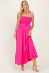 woman wearing a bright pink smocked maxi dress with thin straps and flowing skirt