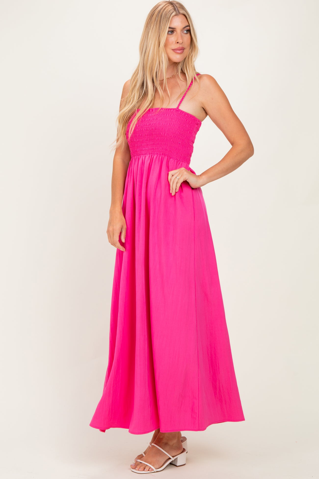 woman wearing a bright pink smocked maxi dress with thin straps and a flowing skirt