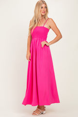 woman wearing a bright pink smocked maxi dress with thin straps and a flowing skirt