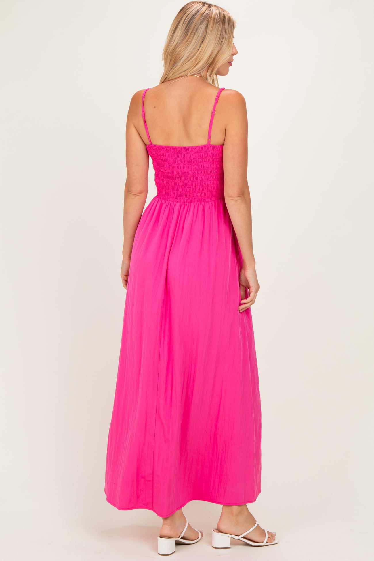 woman wearing a vibrant pink maxi dress with a smocked bodice and adjustable straps, viewed from the back