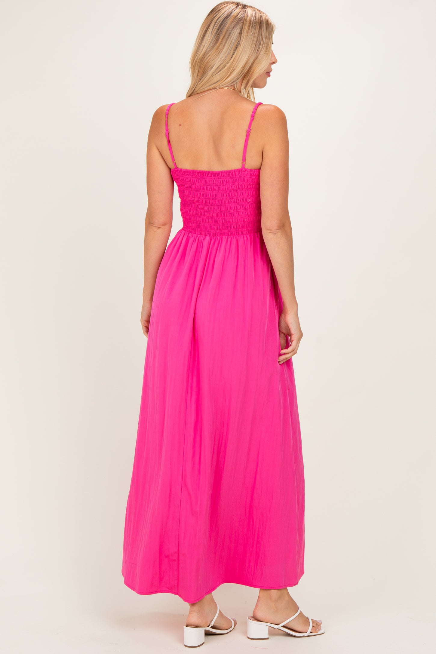 woman wearing a vibrant pink maxi dress with a smocked bodice and adjustable straps, viewed from the back