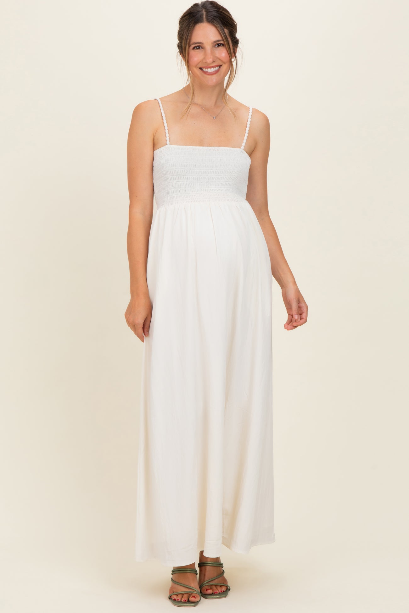 woman wearing a white maternity maxi dress with smocked bodice and adjustable straps, baby bump visible