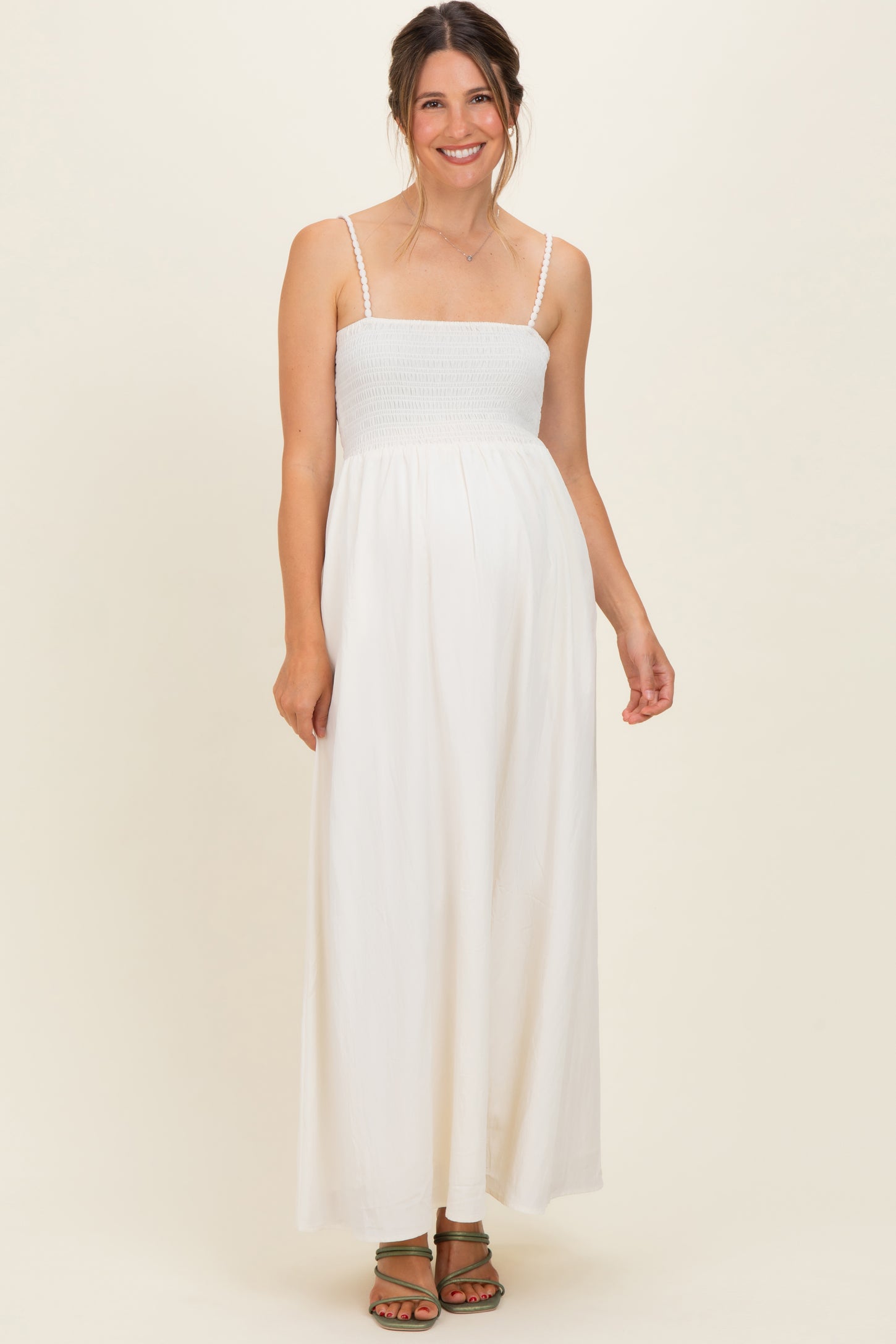woman wearing a white maternity maxi dress with smocked bodice and adjustable straps, baby bump visible