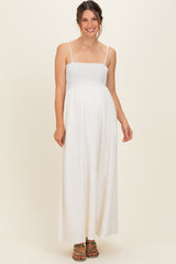 woman wearing a white maternity maxi dress with smocked bodice and adjustable straps, baby bump visible