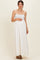 woman wearing a white maternity maxi dress with a smocked bodice and holding her baby bump