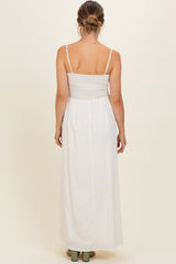 woman wearing a white maternity maxi dress with a smocked bodice and adjustable spaghetti straps, showing her back