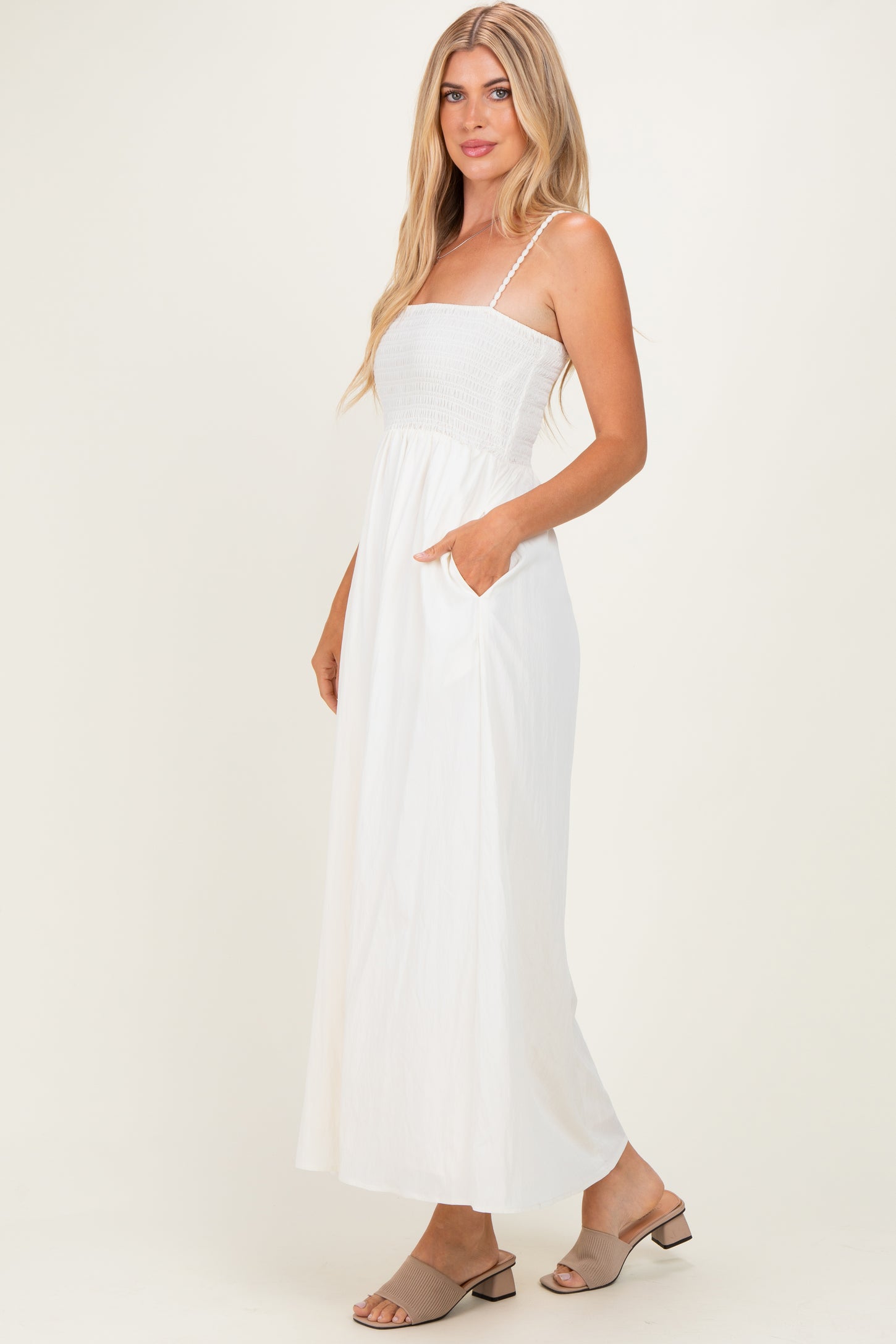 woman wearing a white maxi dress with a smocked bodice and pockets, standing in a casual pose