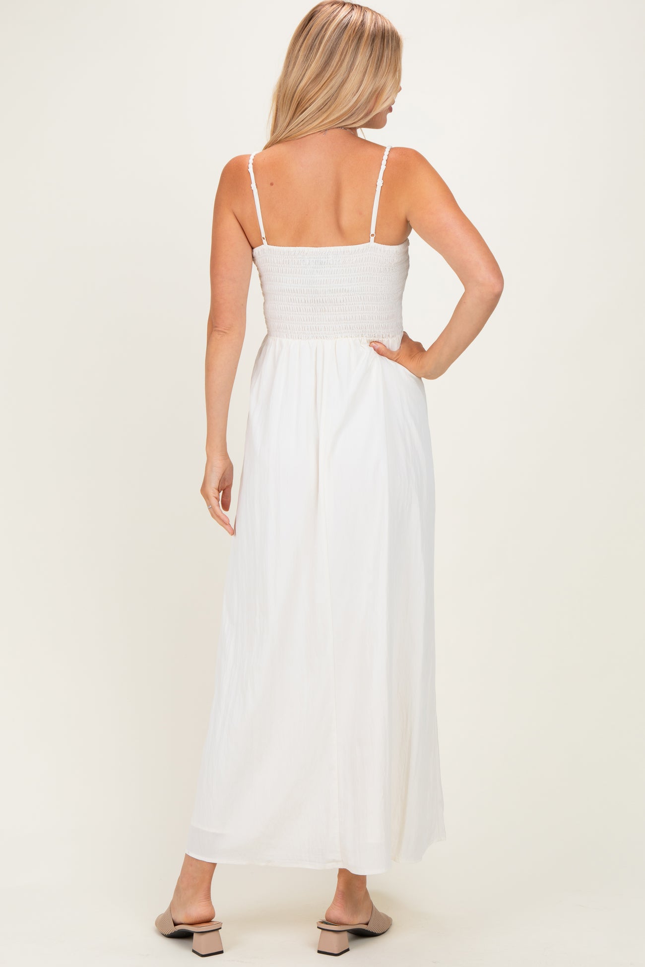 woman wearing a back view of a white maxi dress with a smocked bodice and thin straps