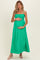 woman wearing a bright green maternity maxi dress with a smocked bodice, holding her baby bump