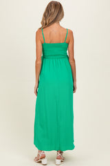 woman wearing a green maternity maxi dress with adjustable straps and smocked back detail