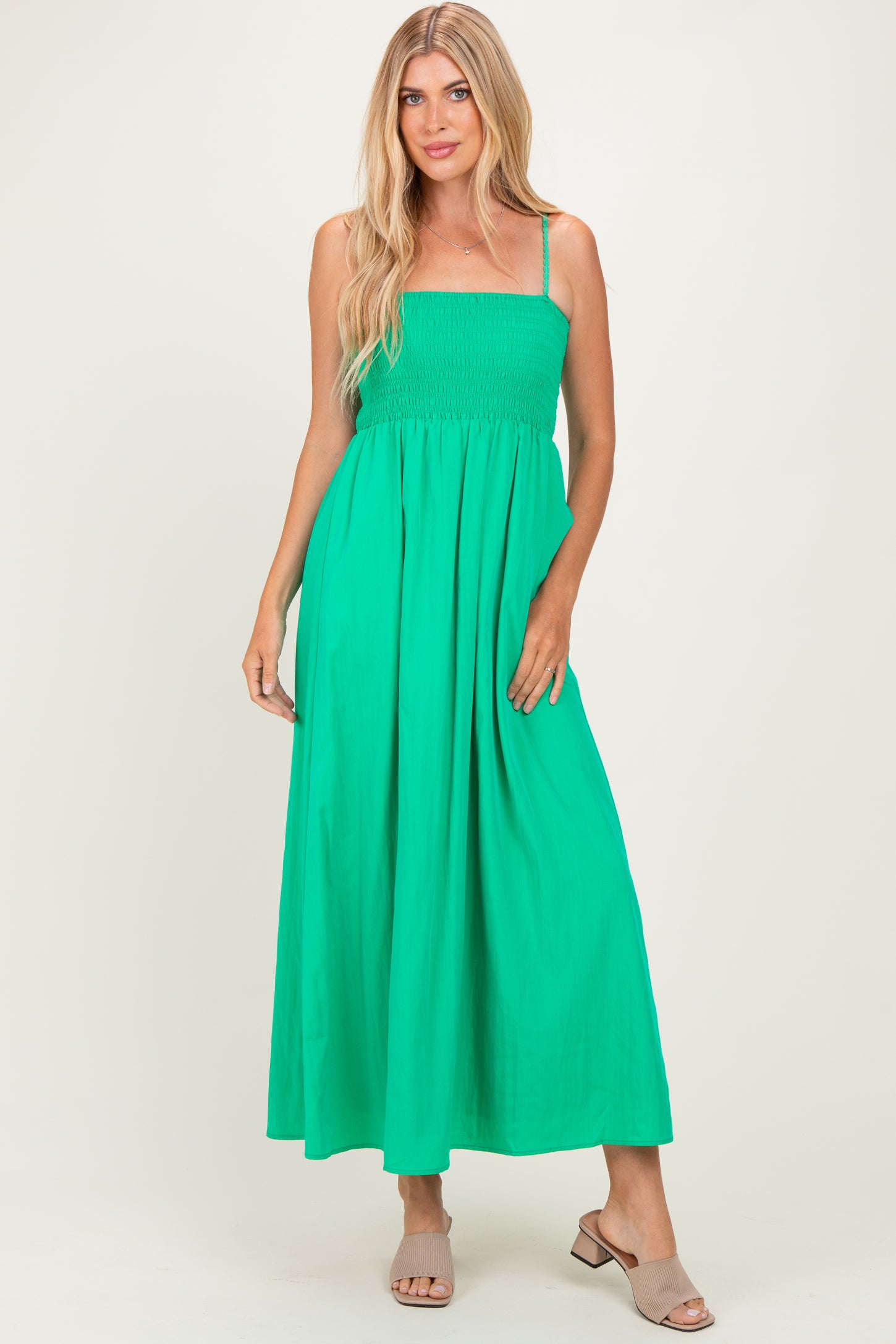 woman wearing a vibrant green smocked maxi dress with thin straps and a flowing skirt
