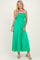 woman wearing a vibrant green smocked maxi dress with thin straps and a flowing skirt