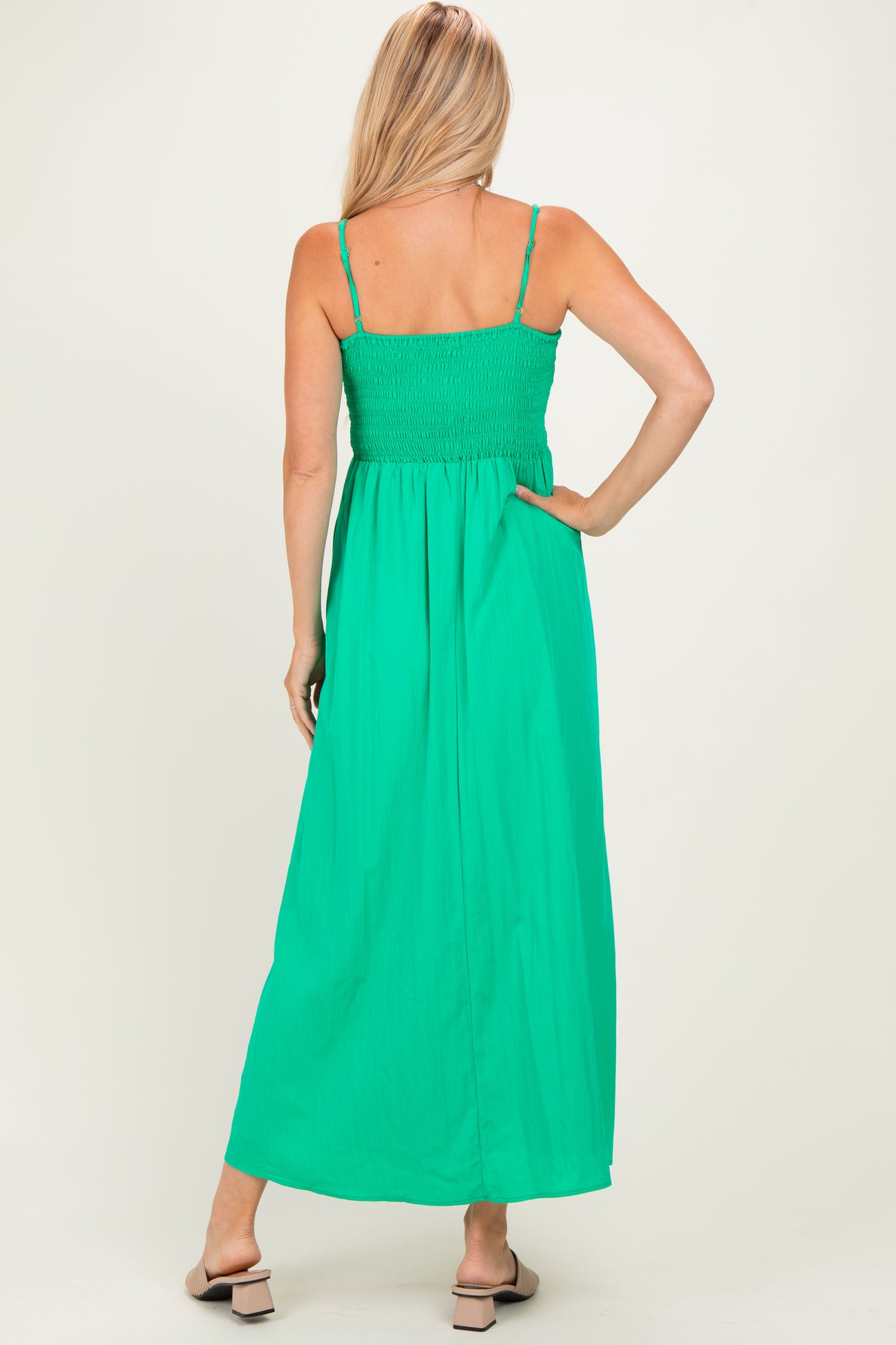woman wearing a vibrant green maxi dress with adjustable straps and a smocked bodice, viewed from the back