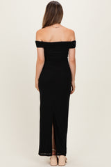 woman wearing a black off-the-shoulder maternity maxi dress with a back slit