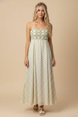 woman wearing a patterned maxi dress with a green and white bodice and a flowing beige skirt