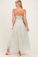 woman wearing a light green and cream patterned maternity maxi dress with adjustable straps, showing her back