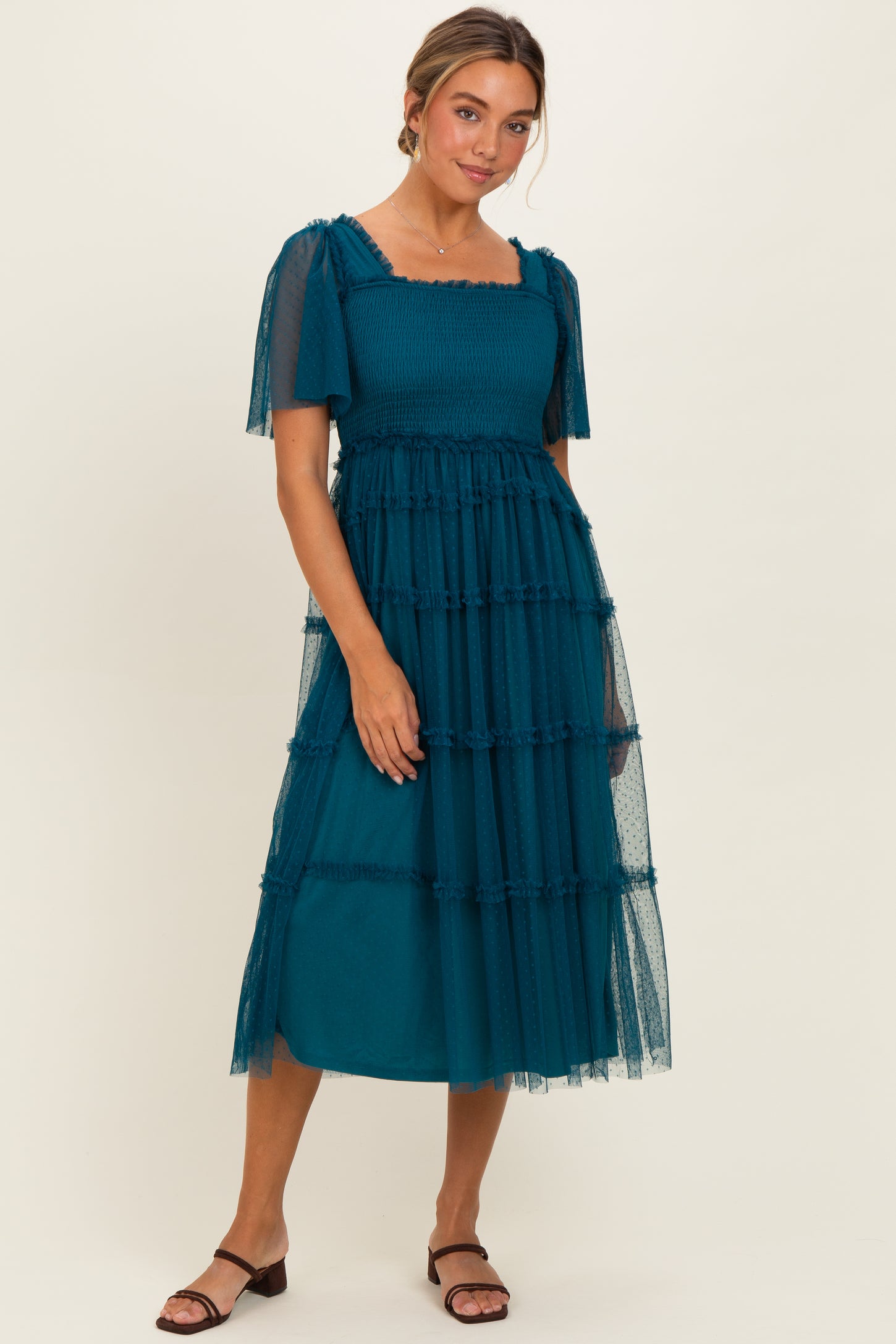 woman wearing a teal smocked midi dress with sheer puff sleeves and ruffled tulle layers