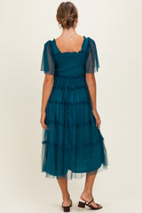 woman wearing a teal tiered midi dress with sheer short sleeves and a smocked bodice, viewed from the back