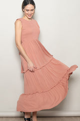 woman wearing a dusty rose sleeveless maxi dress with ruffle details and a flowing skirt