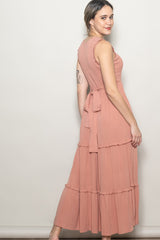 woman wearing a dusty rose tiered maxi dress with a tie waist and textured bodice, posing sideways against a neutral background
