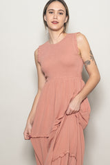 woman wearing a dusty pink sleeveless dress with ruffle details and a flowing skirt