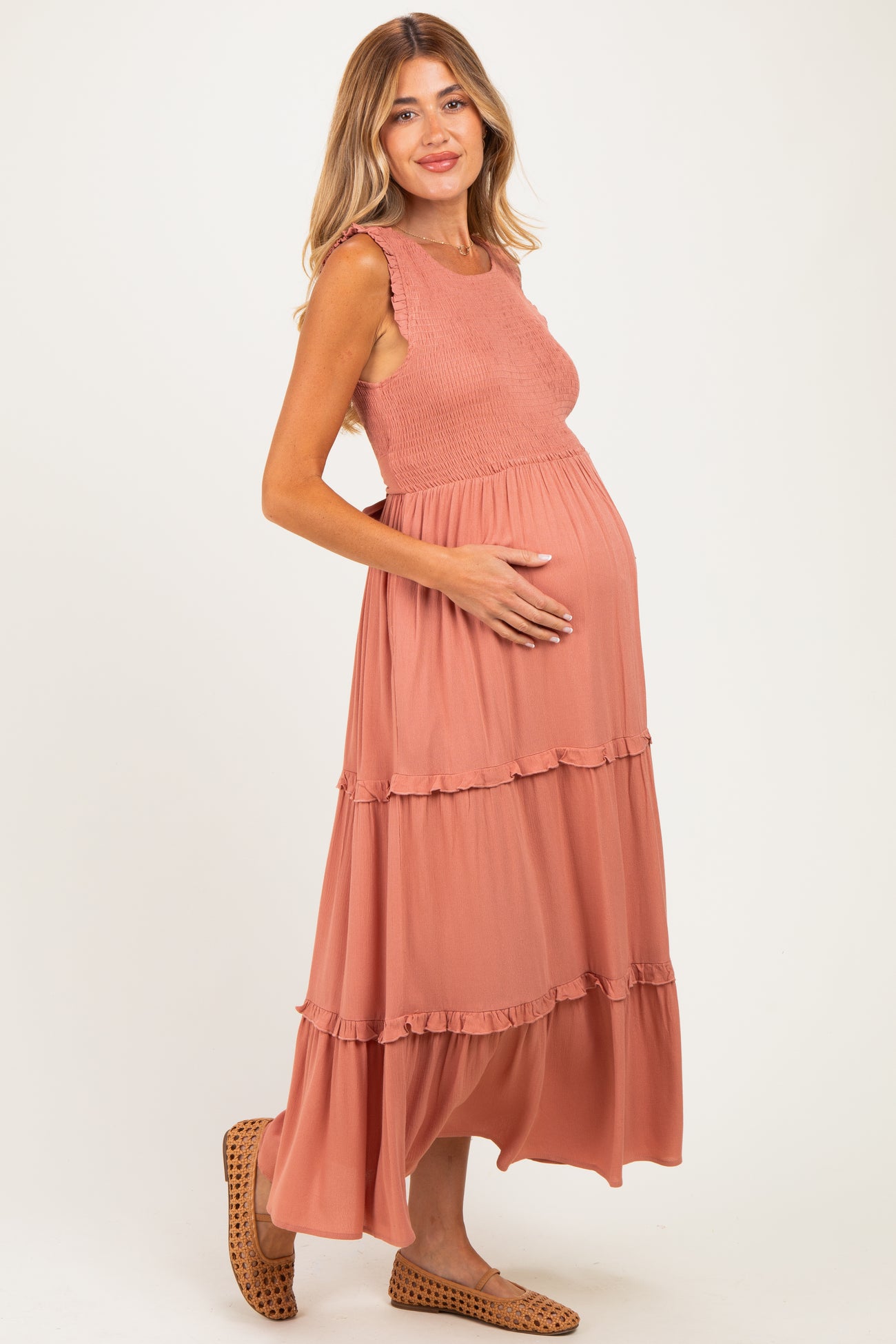 woman wearing a rust-colored maternity maxi dress with ruffle details and a visible baby bump