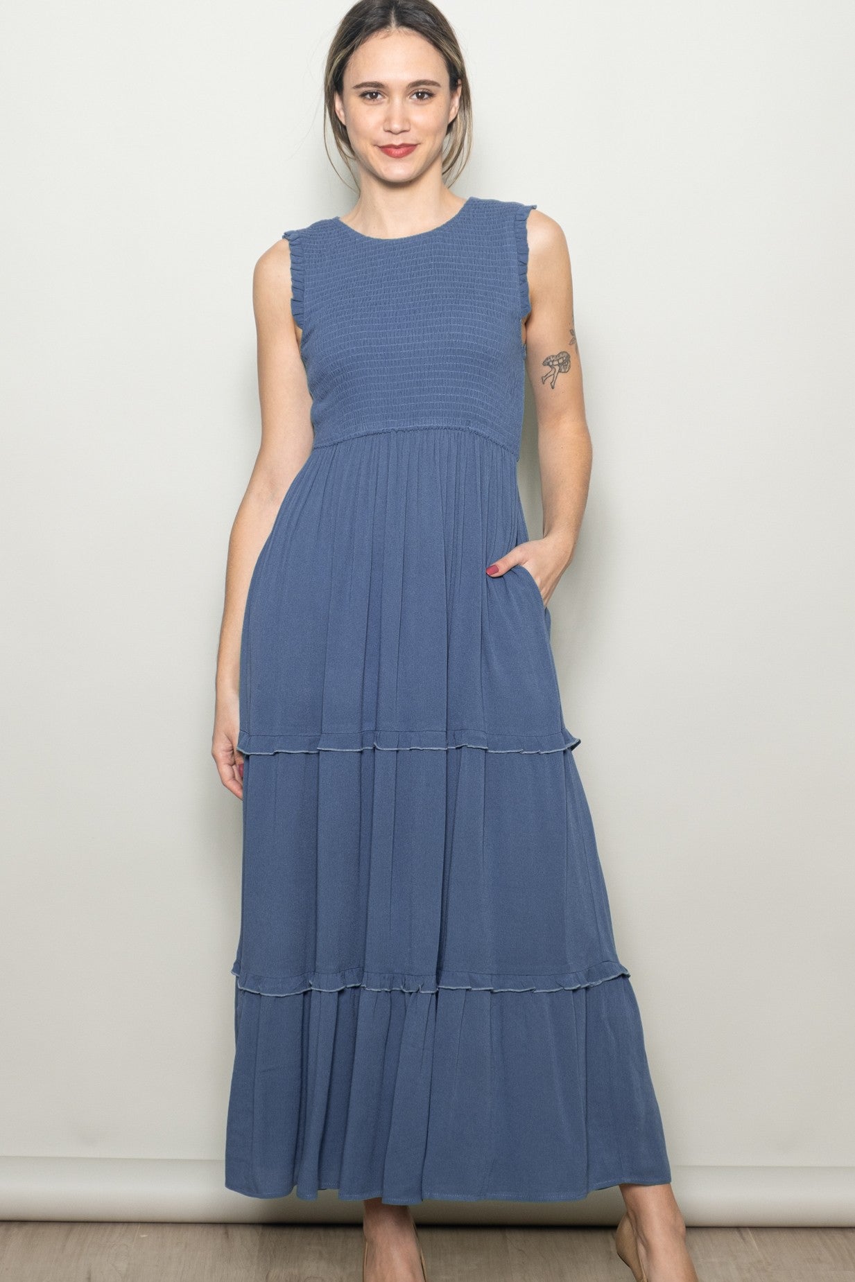 woman wearing a blue sleeveless maxi dress with tiered ruffles and pockets