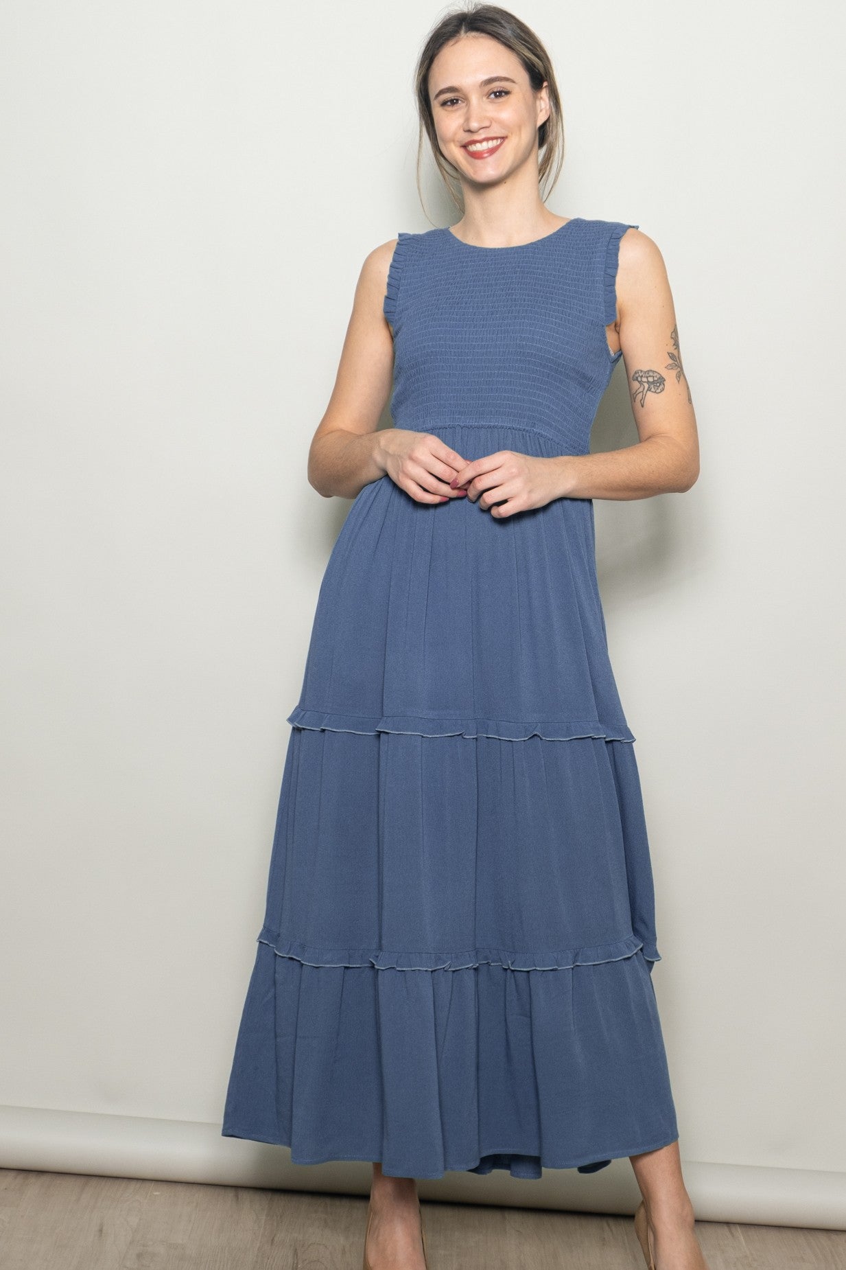 woman wearing a blue tiered maxi dress with a textured bodice and ruffled shoulder details