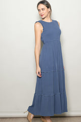 woman wearing a sleeveless blue maxi dress with ruffle details and tiers at the skirt