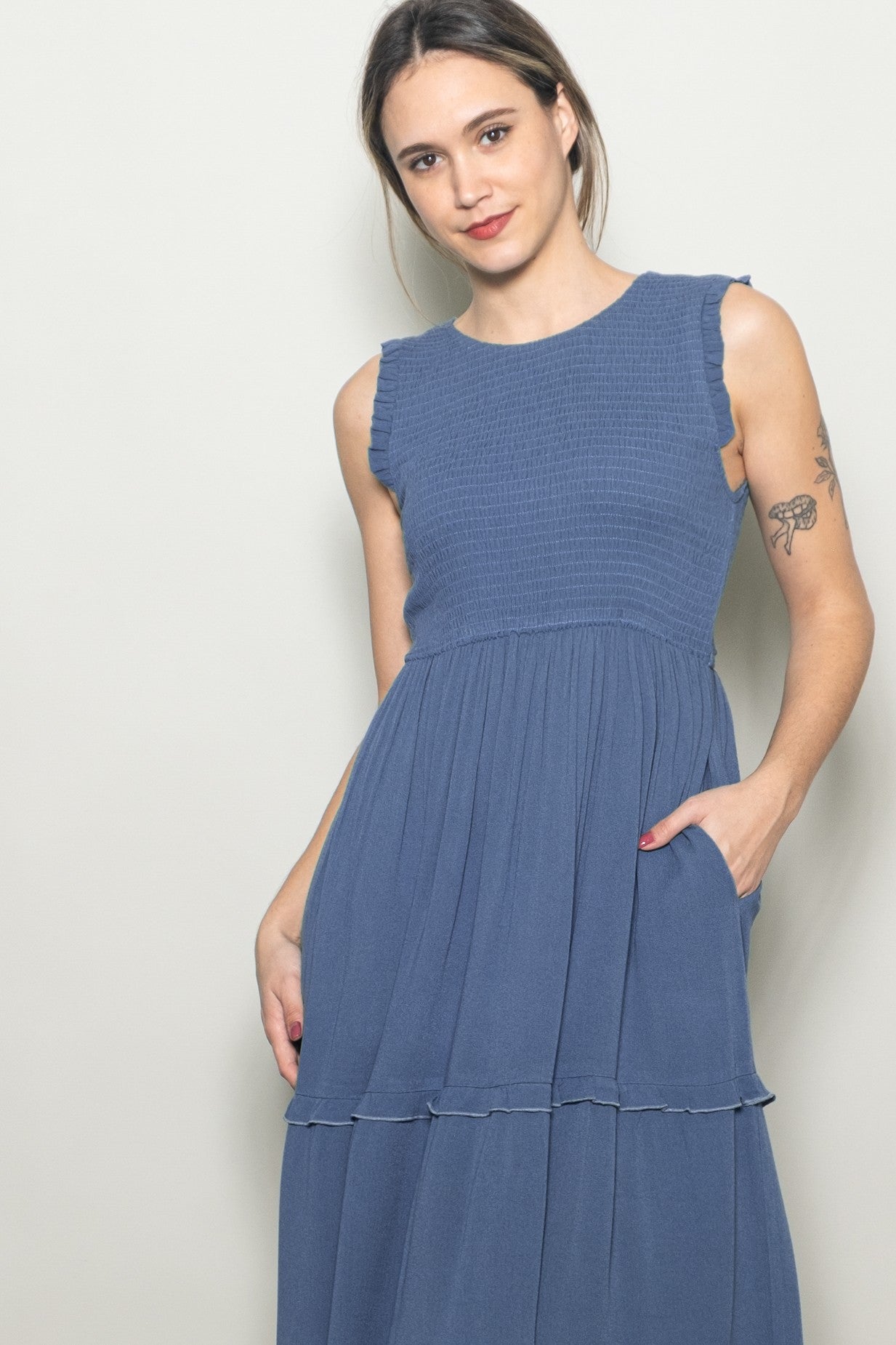 woman wearing a blue sleeveless tiered dress with ruffle details and pockets