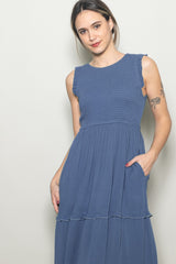 woman wearing a blue sleeveless tiered dress with ruffle details and pockets