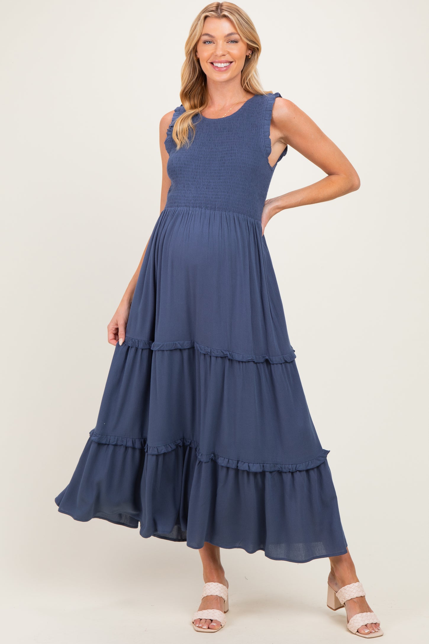 woman wearing a navy blue maternity dress with smocked bodice and tiered ruffled skirt, showcasing her baby bump
