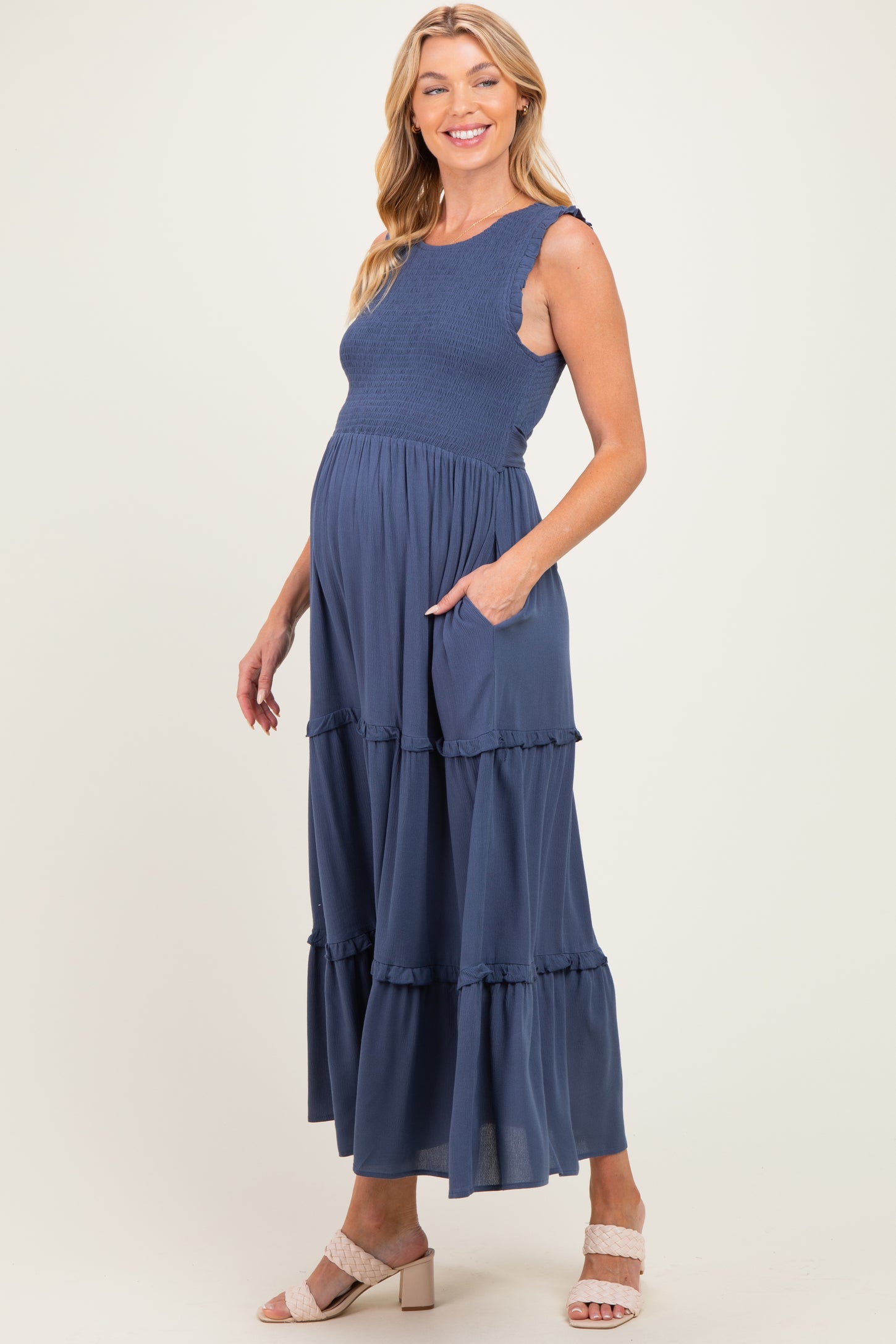 woman wearing a navy blue maternity maxi dress with ruffle tiers and pockets, showcasing her baby bump
