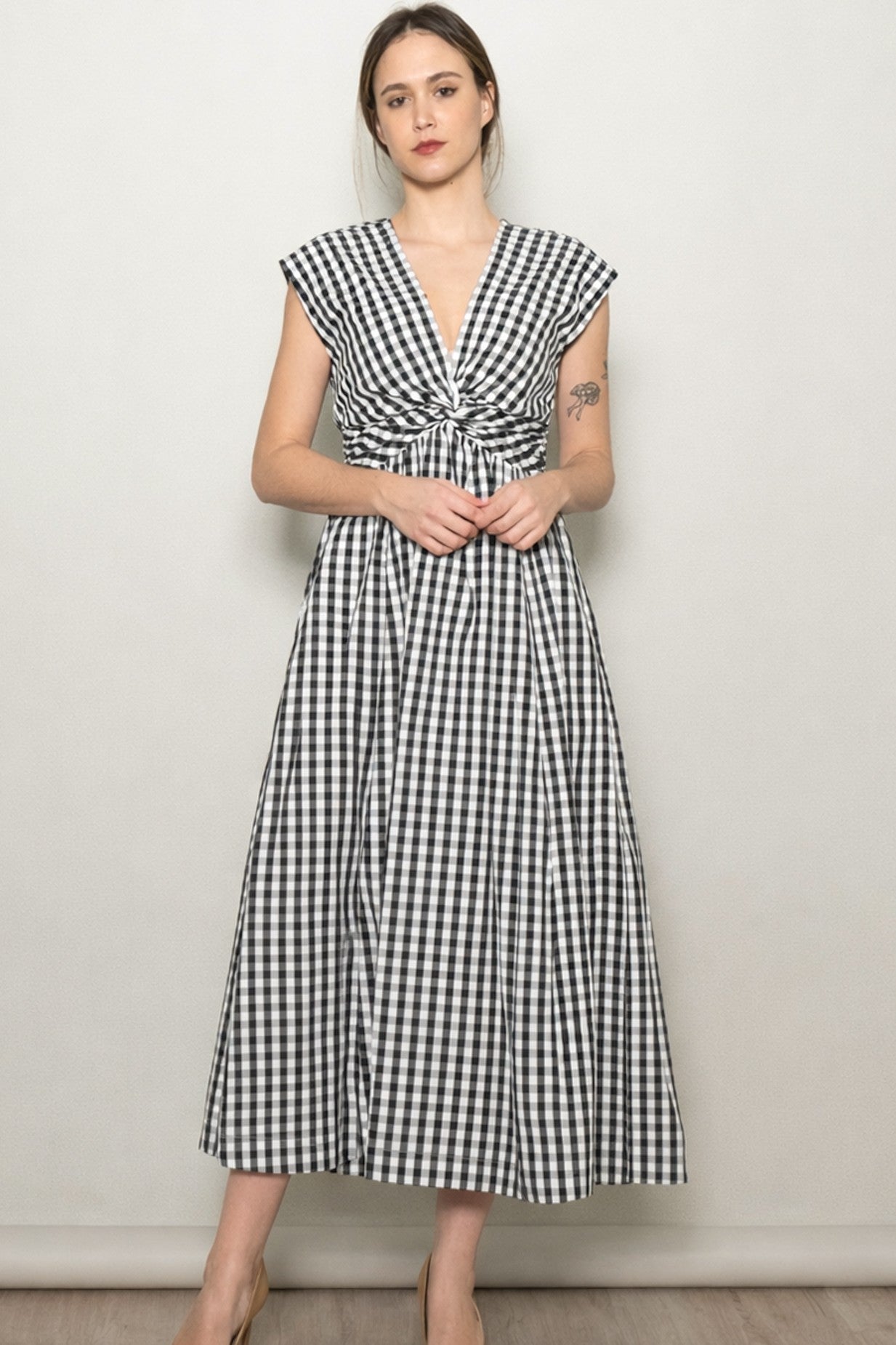 woman wearing a black and white gingham maxi dress with cap sleeves and a twisted front detail