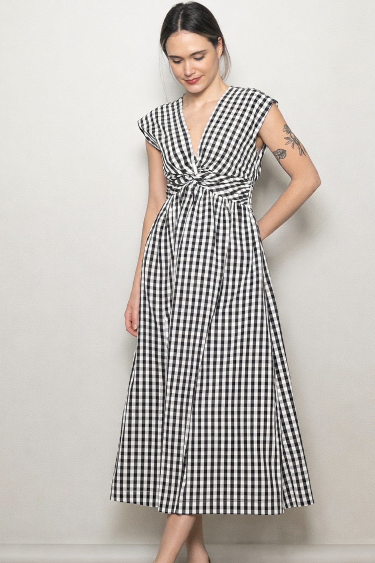 woman wearing a black and white checkered maxi dress with a knotted front and cap sleeves