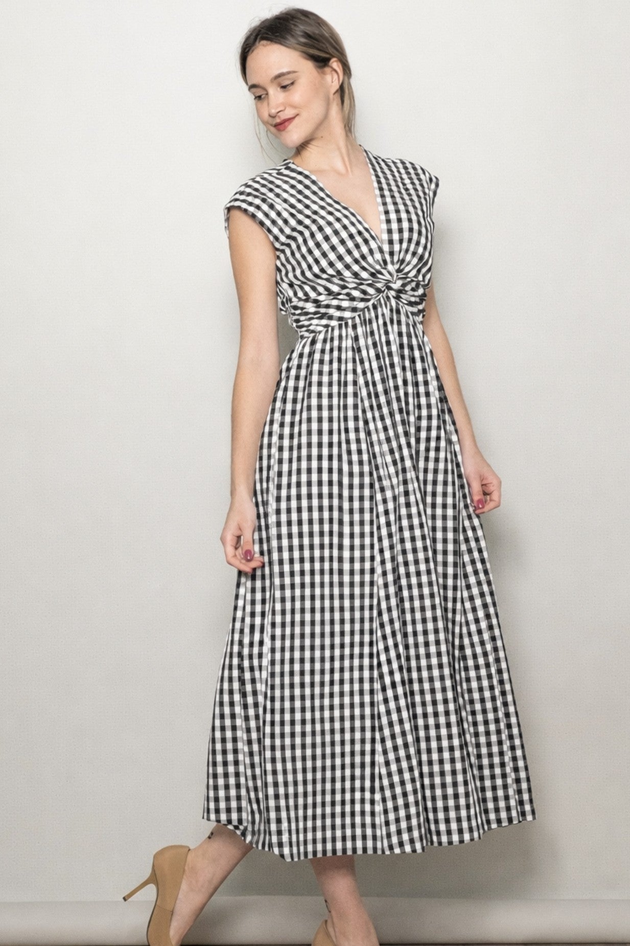 woman wearing a black and white gingham maxi dress with a twisted front detail and cap sleeves