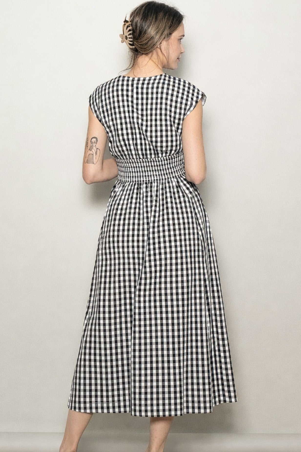 woman wearing a black and white gingham maxi dress with a smocked back and cap sleeves, viewed from the back