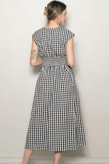 woman wearing a black and white gingham maxi dress with a smocked back and cap sleeves, viewed from the back