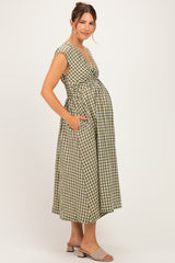 woman wearing a green and white gingham maternity dress with pockets and a fitted bodice, showcasing a baby bump